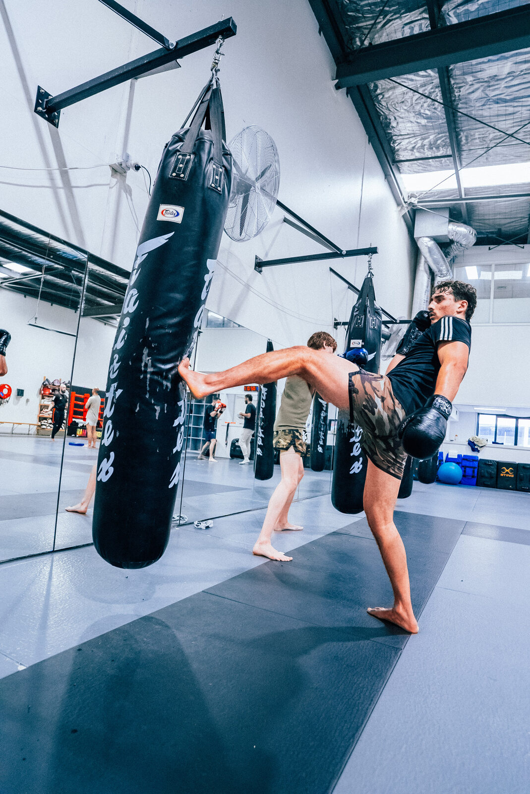 High kick to the heavy bag during a CPT class