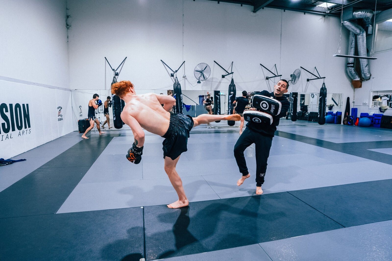 Student landing a head kick on the coaching pads