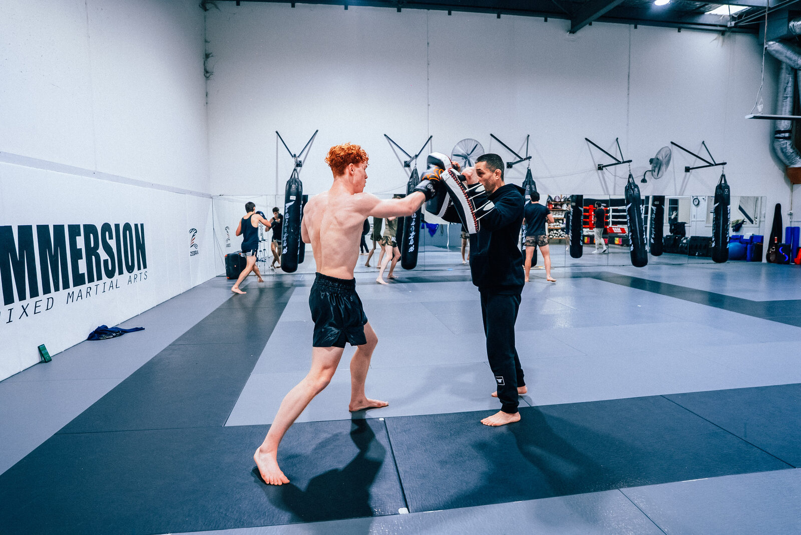 Student throwing a jab into the focus mitts at Immersion