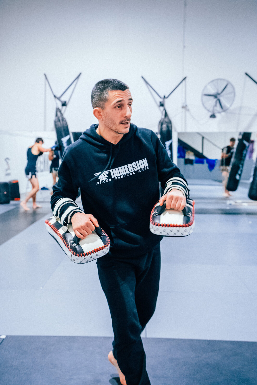 Sotir Kichukov carrying Thai pads between rounds